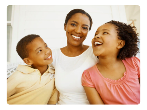A Black mother and two children are laughing.